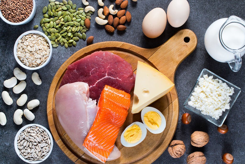 Alimentos ricos en proteína sobre una mesa: huevos, pescado, carne, legumbres, frutos secos y semillas
