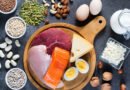Alimentos ricos en proteína sobre una mesa: huevos, pescado, carne, legumbres, frutos secos y semillas