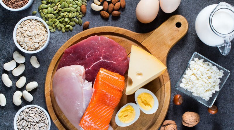 Alimentos ricos en proteína sobre una mesa: huevos, pescado, carne, legumbres, frutos secos y semillas
