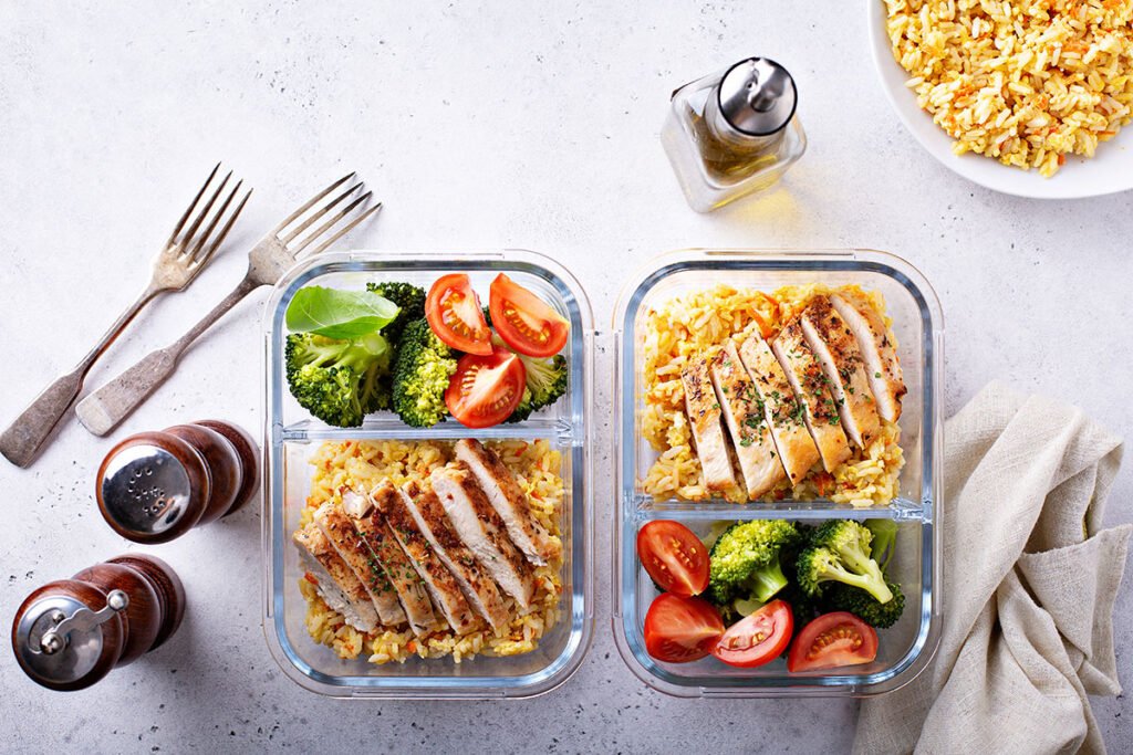 Recipientes de batch cooking con pollo, arroz integral y verduras listos para la semana