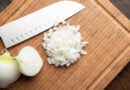 Cebolla blanca fresca picada sobre tabla de cortar de madera
