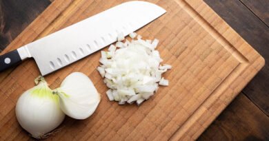 Cebolla blanca fresca picada sobre tabla de cortar de madera