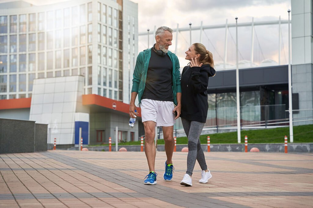 Pareja caminando al aire libre después de entrenar, hábito clave para reducir la grasa abdominal