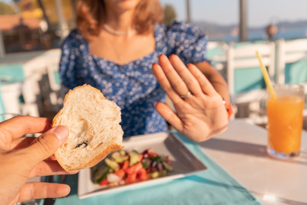 Mujer rechazando una tostada de pan en un restaurante, una escena habitual para quien convive con los síntomas de celiaquía