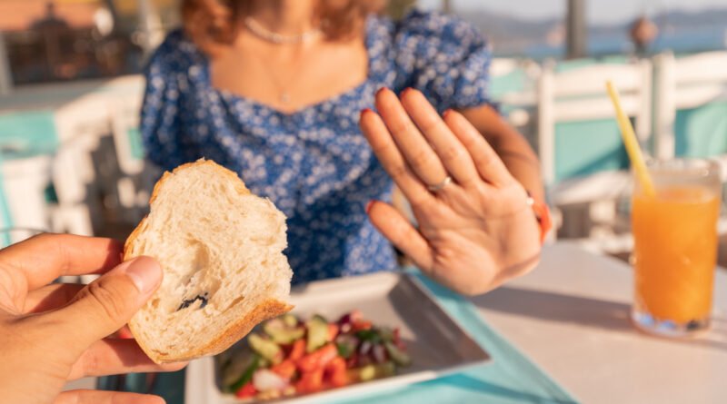 Mujer rechazando una tostada de pan en un restaurante, una escena habitual para quien convive con los síntomas de celiaquía