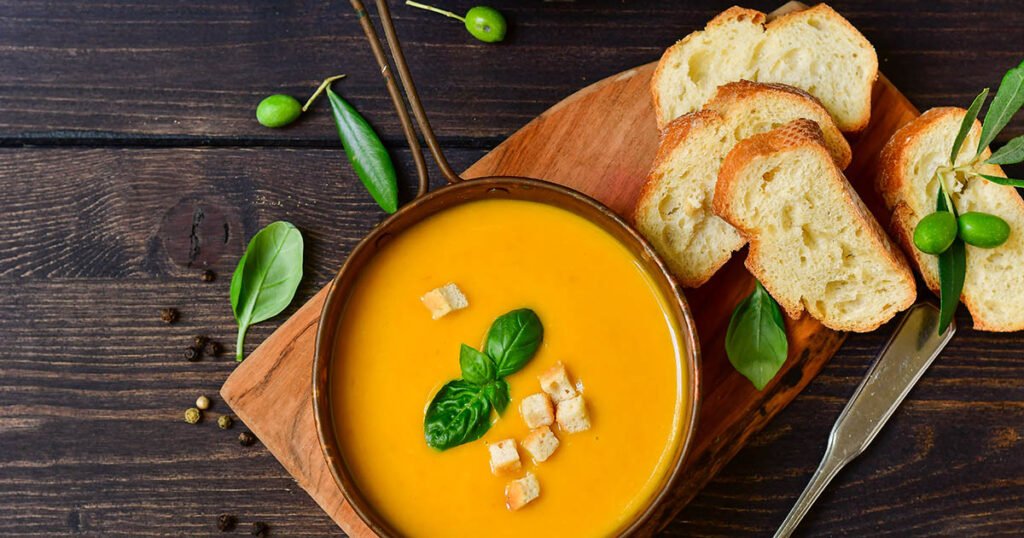 Bol de sopa de calabaza con albahaca y crackers crujientes, receta vegana