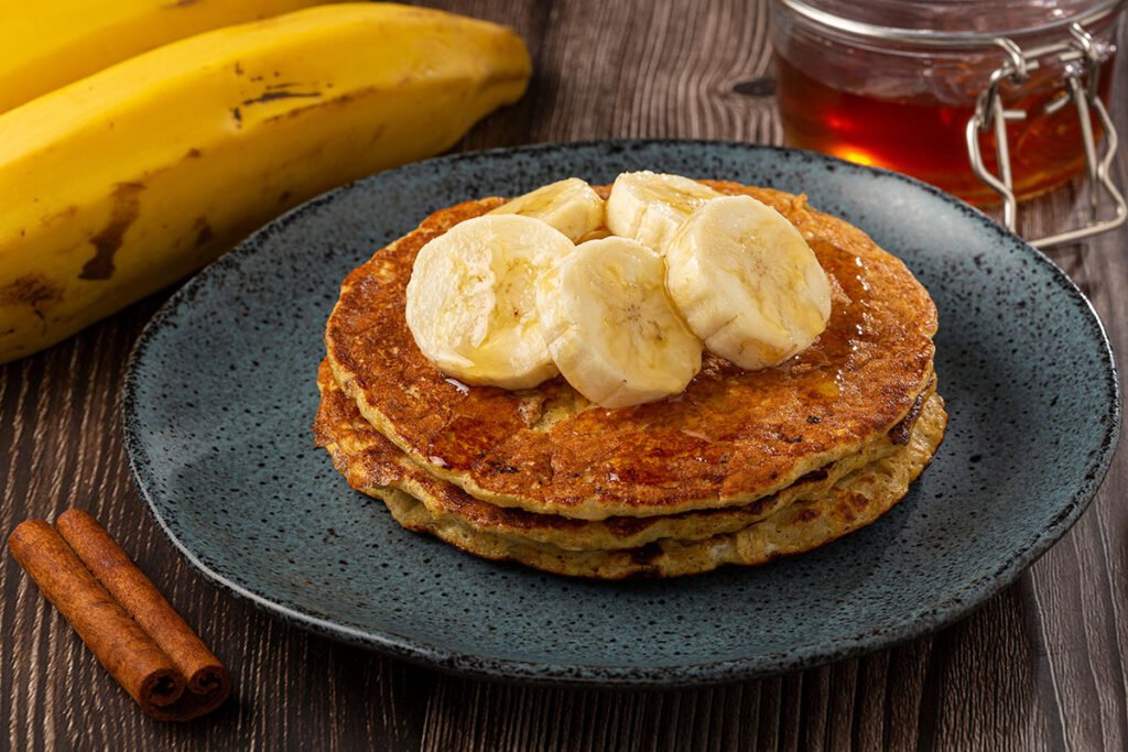 Tortitas sin harina de banana y avena, servidas con rodajas de banana y miel