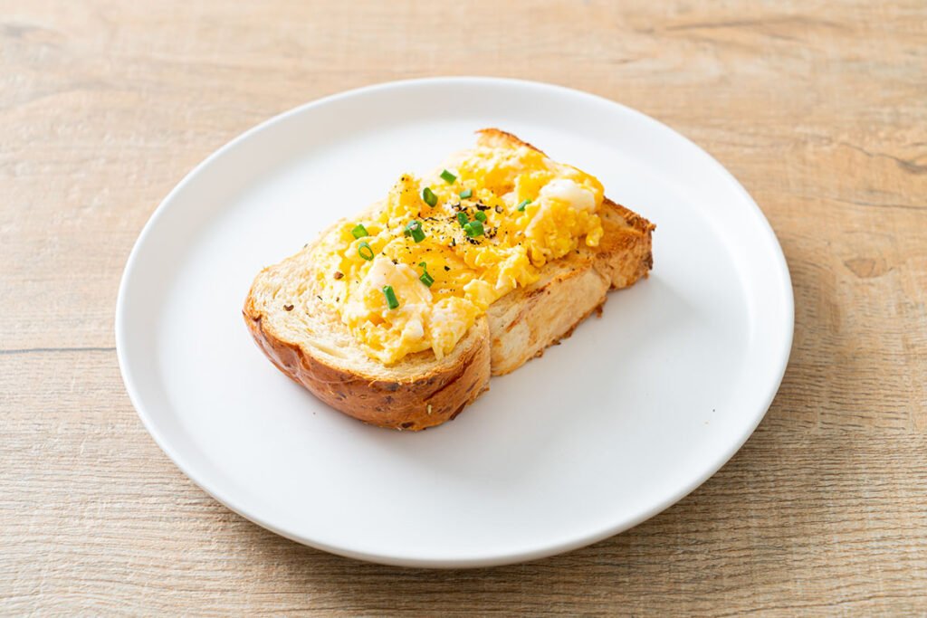 Huevos revueltos cremosos servidos sobre una tostada de pan integral