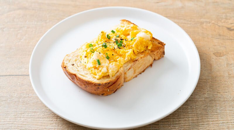 Huevos revueltos cremosos servidos sobre una tostada de pan integral