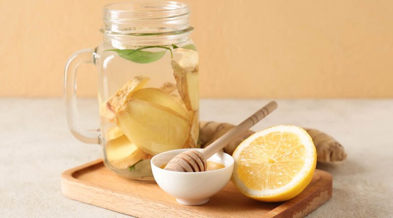 Bebida de jengibre fresco con limón y miel sobre tabla de madera