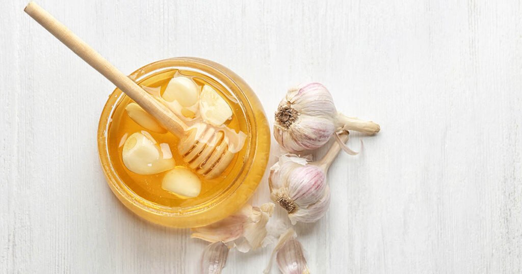 Frasco de miel con ajo sobre fondo de madera blanca