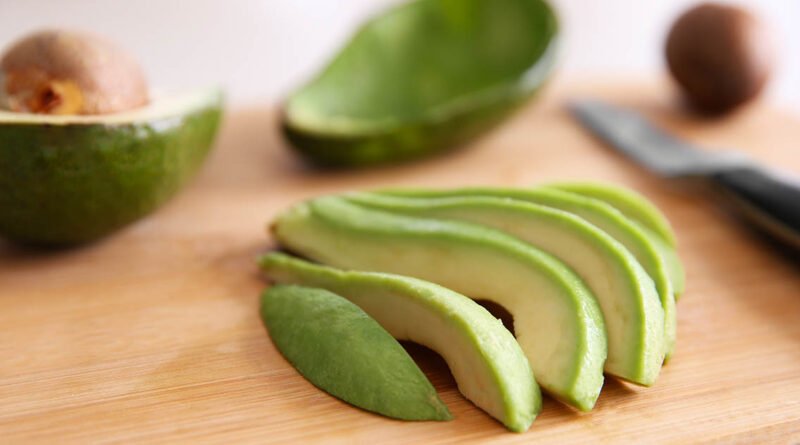 Palta fresca cortada en fetas sobre tabla de cortar