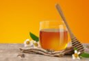 Frasco de miel con abeja y cuchara de madera, productos de la colmena