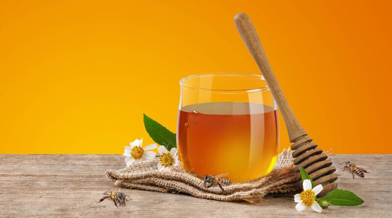 Frasco de miel con abeja y cuchara de madera, productos de la colmena