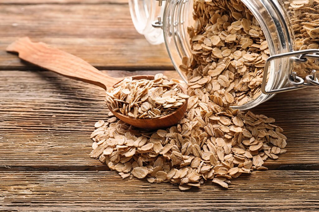 Frasco de vidrio y cuchara con copos de avena sobre una mesa de madera