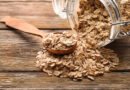 Frasco de vidrio y cuchara con copos de avena sobre una mesa de madera