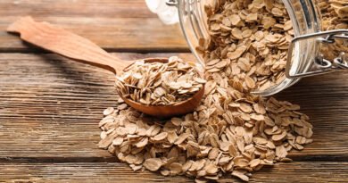 Frasco de vidrio y cuchara con copos de avena sobre una mesa de madera